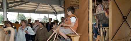 Einige Kinder erkunden eine rekonstruierte römische Kutsche.