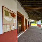Der überdachte Bereich vor den Häusern mit einem auf die Wand gemalten Ladenschild der Weberei.