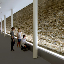 Drie jongeren bekijken een antieke muur in het RömerMuseum. 
