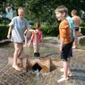 Zwei Jungen spielen mit dem kleinen Damm des Wasserspielplatzes.